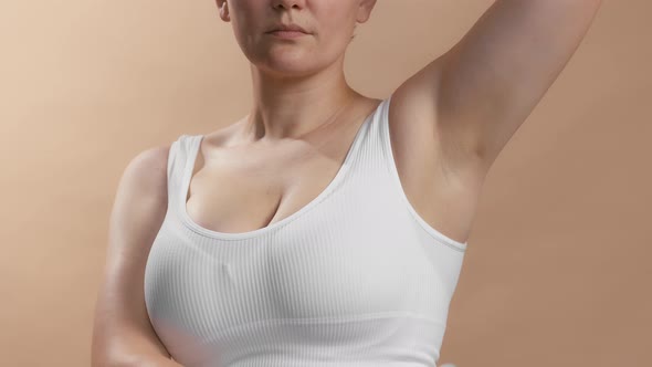 Caucasian Anonymous Young Woman in White Top Spraying Deodorant on Her Underarm