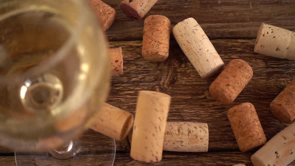Wine corks fall on an old wooden board against the backdrop of a glass of wine. Slow motion. alt