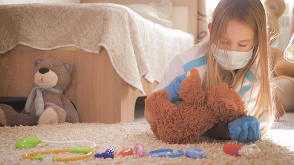Beautiful Little Girl Playing Doctor with Teddy Bear at Home alt