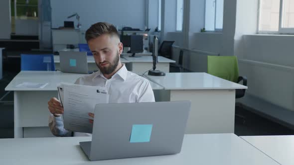 Young Man Looks Through His Paper Work in Company alt
