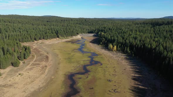 Aerial drone flying above a lake with no water that was affected by drought. alt