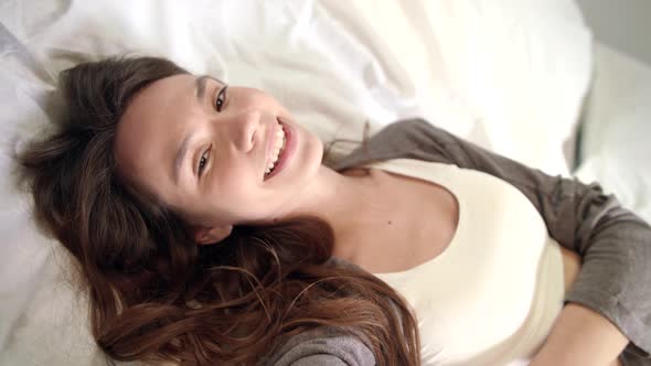 Woman Flirting with Camera in Bed. Portrait of Happy Girl Relaxing in Bedroom alt