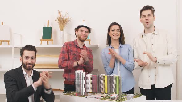 A Team of Architects Standing at a Desk in the Office Claps Their Hands