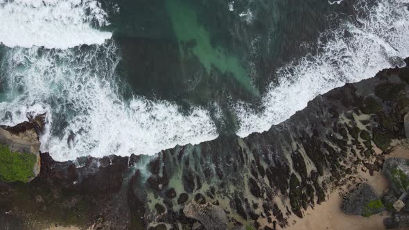 Top down aerial view of giant ocean waves crashing and foaming in coral beach alt