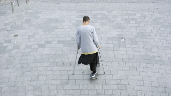 Top View of the Skill Man with One Leg on Crutches Spinning on His Skateboard Doing Tricks alt