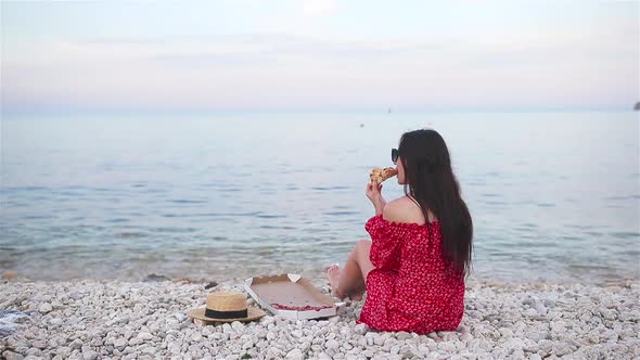 Woman Having a Picnic with Pizza on the Beach alt