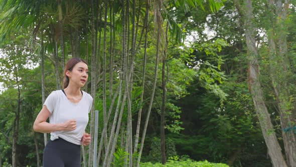 Asian young beautiful sport woman running on street in public park. alt
