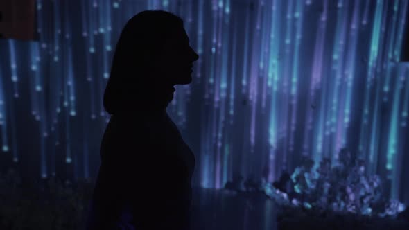 A Girl Stands Against a Background Projection of Falling Rays