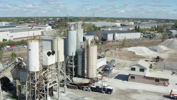 Cement Factory Buildings and Big Reservoirs with Materials Against Industrial Town at Hills Foot on alt