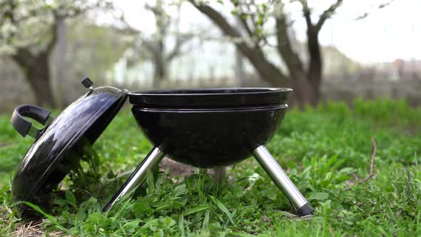 Barbecue Grill Stands in a Meadow Among the Green Grass