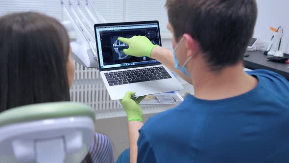 Dentistry Doctor Talking About Surgery Showing Xray on Monitor To Patient