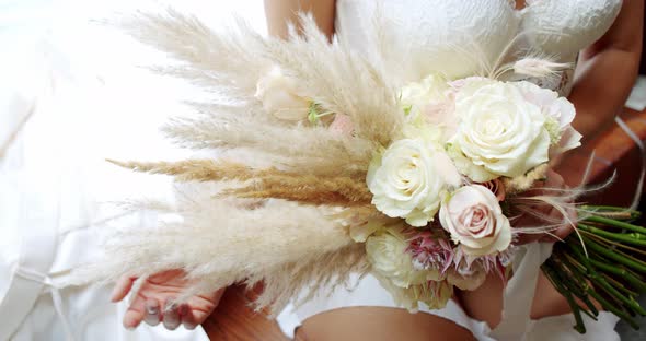 Bride in Lingerie and Holds a Bouquet of Flowers. Bride's Morning. Close Up alt