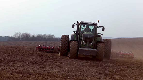 Modern tractor plows a field, moving for the camera. alt