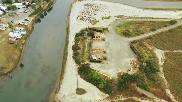 A rotating aerial view of a set of waterfront oil pumpjacks. alt