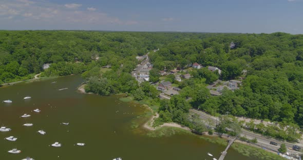 Aerial Pan from Boats Anchored on Harbor to a Small Town Amongst Trees alt