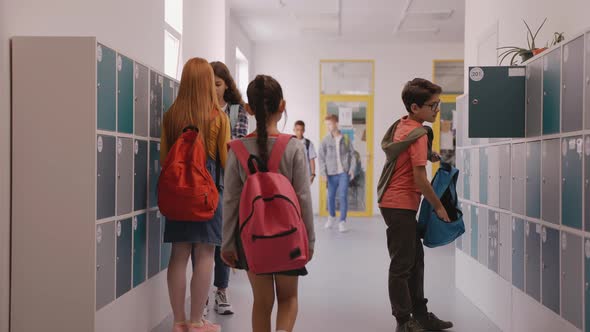 Children Walk in School Hallway Boy Closes His Locker alt