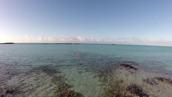 Aerial shot of young woman sup standup paddleboarding in the Caribbean. alt