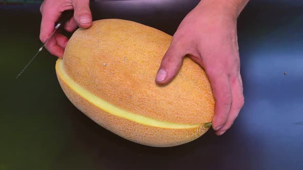 Slicing ripe melon with a kitchen knife.