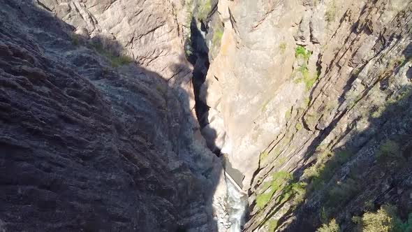 Aerial Pan From Deep Canyon and River to Walking Bridge Overlooking Small Mountain Town of Ouray alt