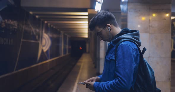 Guy Looks Into the Phone and Waits for the Train Metro Station alt