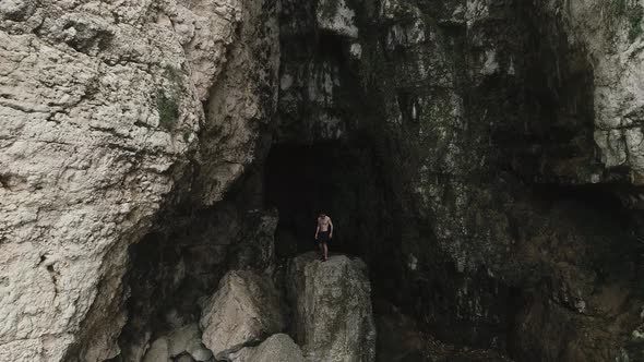 Aerial forward view of guy who comes out of the shadows and climbs a cliff to dive. Chekka, Lebanon. alt