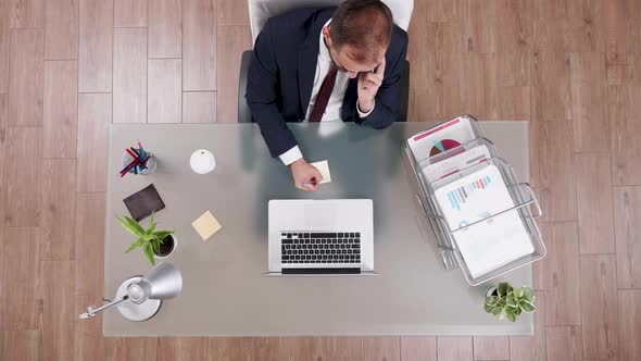 Top View of Businessman in Suit Talking on the Phone and Making Notes alt