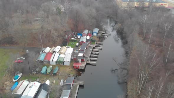 Small Harbor With Shed Buildings River Canal Scene Pull Back Rising Aerial