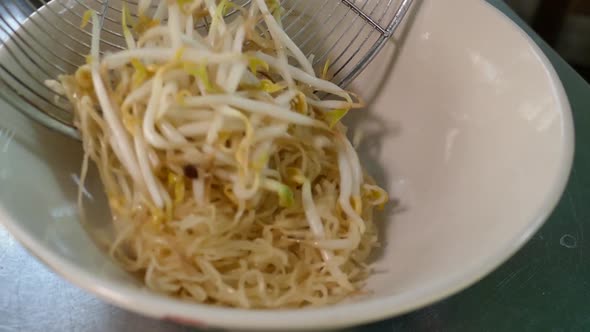 Close-Up Footage of Chef Adding Egg Noodles and Bean Sprouts into Bowl alt
