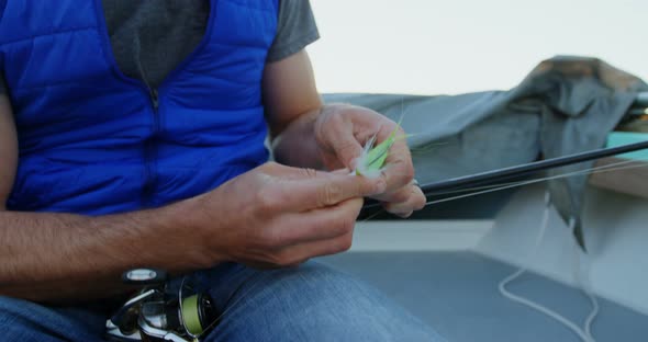 Man tying bait on fishing rod  alt