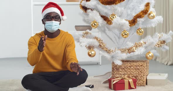 Webcam View Young Black Guy African American Man in Glasses in Yellow Sweater and Santa Hat Sits alt