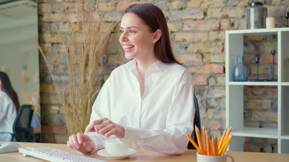 Young Peaceful Businesswoman Having a Cup of Tea at Her Working Place alt