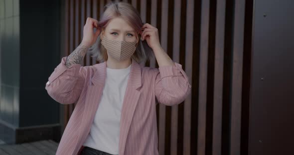 Portrait of Beautiful Young Blonde Putting on Reusable Mask Indoors at Home alt