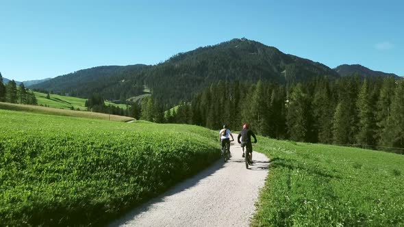 Two people cycling in landscape, Alta Badia, Italy