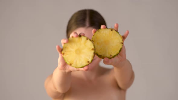 Young healthy smile woman holding slices of juicy pineapple smiling and enjoying natural skin care