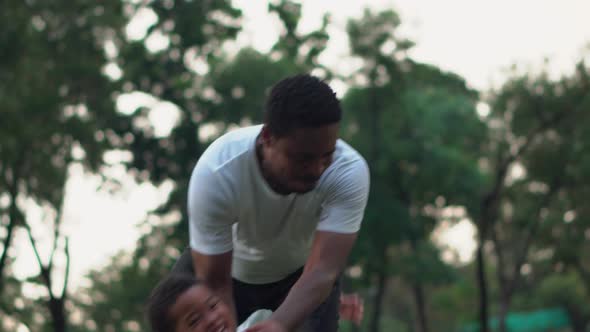 Dark sons and dad playing in park, African American father and two son play in park