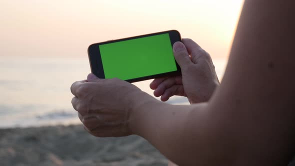 Smart Phone With Green Screen Display Holding On The Beach By Sunrise 4K Video