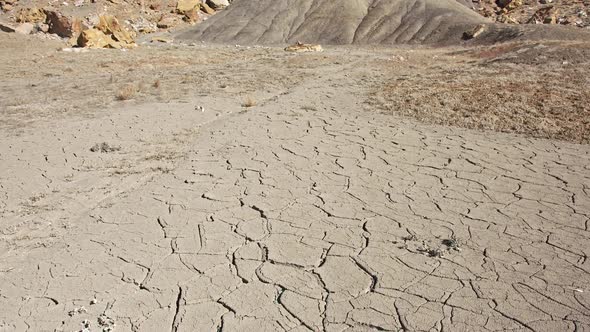 Dry cracked soil at the base of a cliff in the desert alt