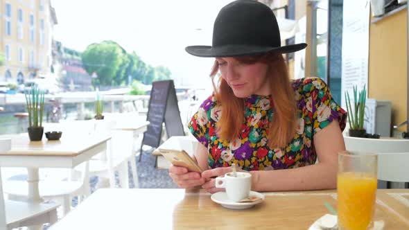 Adult woman outdoor sitting bar using smartphone alt