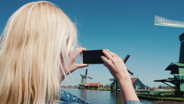 Rear View: A Young Woman Is Photographing Old Windmills in the Netherlands alt