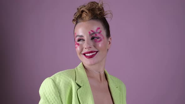 Young Beautiful Woman Professional Make Up Artist with Lipstick Marks Smile at Pink Background alt