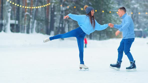 Girl in Hat Skates with Happy Guy on Outdoor Ice Rink