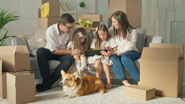 A Happy Family Uses a Tablet for Online Shopping, Sitting on the Couch at Home alt