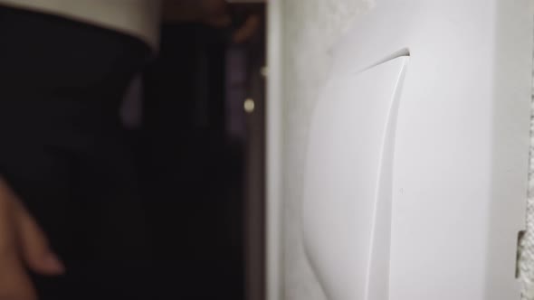Woman Presses Switch Key to Turn on Light Coming Into Room alt