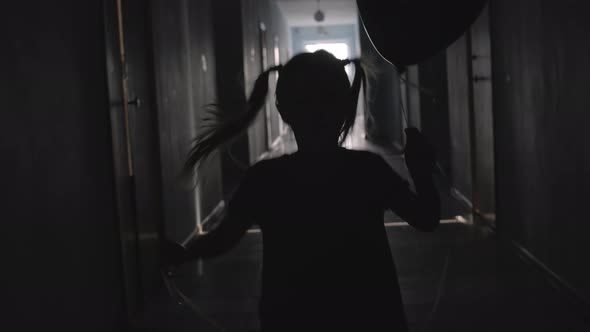 Silhouette of Little Girl Holding Balloon and Running along Hallway