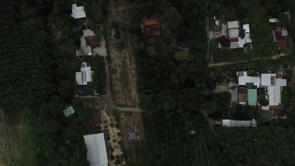 Aerial top down shot of Cu Chi, Vietnam with greenhouse farm houses, forests on sunny day with blue alt