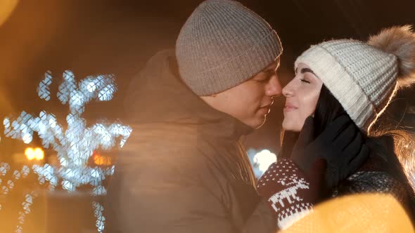 Young Couple Kisses Under Holiday Winter Illumination at Night alt
