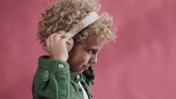 Little Boy Wearing Big Headphones and Nodding His Head Side View