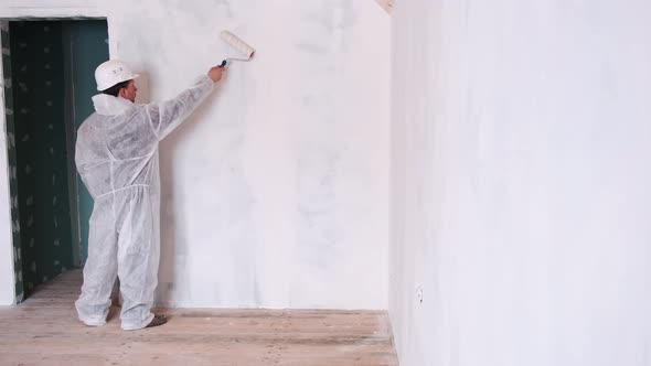 A Man Moves a Roller for Painting Walls on a Wall