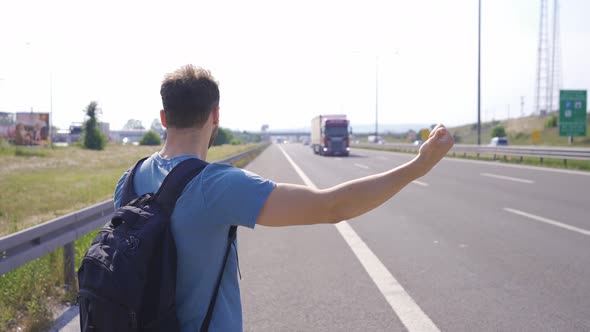 Tourist hitchhiking by the highway. alt