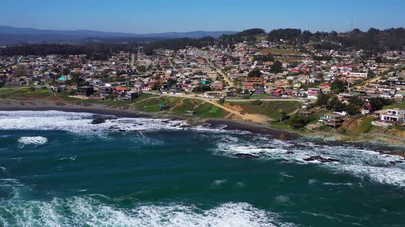 aerial: view of infiernillo beach in the city of pichilemu also overlooking the town with black sand alt